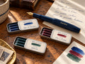 Three tins, Nº 001 Bleu de Chartres, Nº 002 Cire à Cacheter and Nº 003 Giboulée, with a Kaweco pen