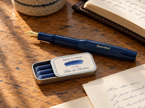 Tin Nº 001 Bleu de Chartres open beside a navy Kaweco pen and handwritten letters